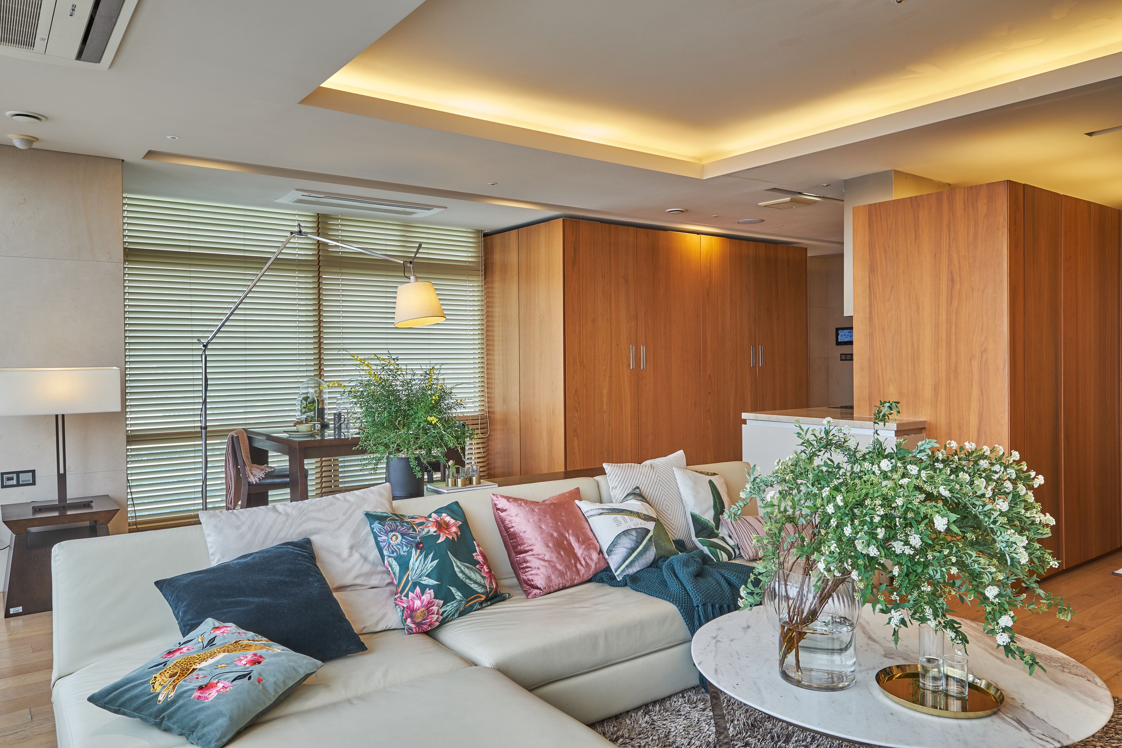 Una sala de estar moderna con un sofá modular, almohadones decorativos, una mesa de centro redonda y una planta en maceta.