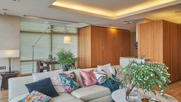 Una sala de estar moderna con un sofá modular, almohadones decorativos, una mesa de centro redonda y una planta en maceta.