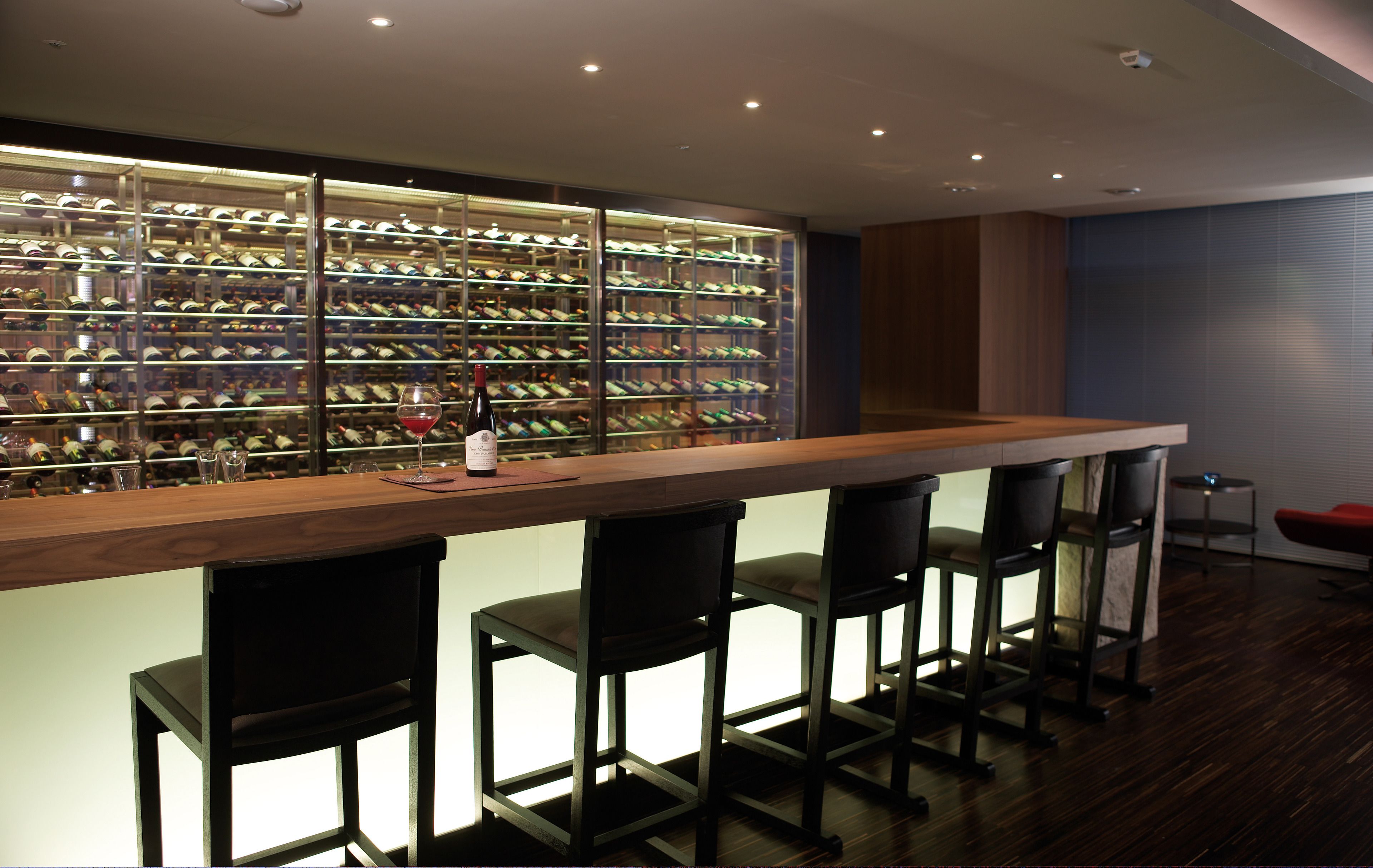 A bar area with a wine rack and bar stools.
