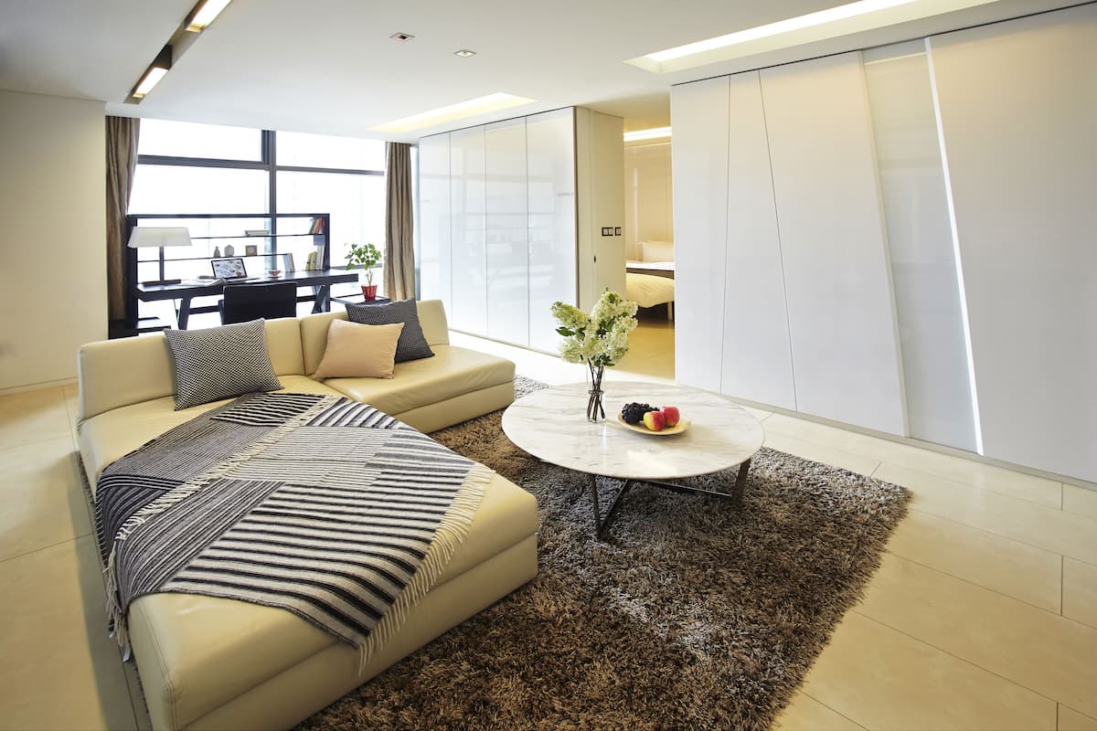 A modern living room with a sofa, coffee table, and a view of a cityscape through large windows.