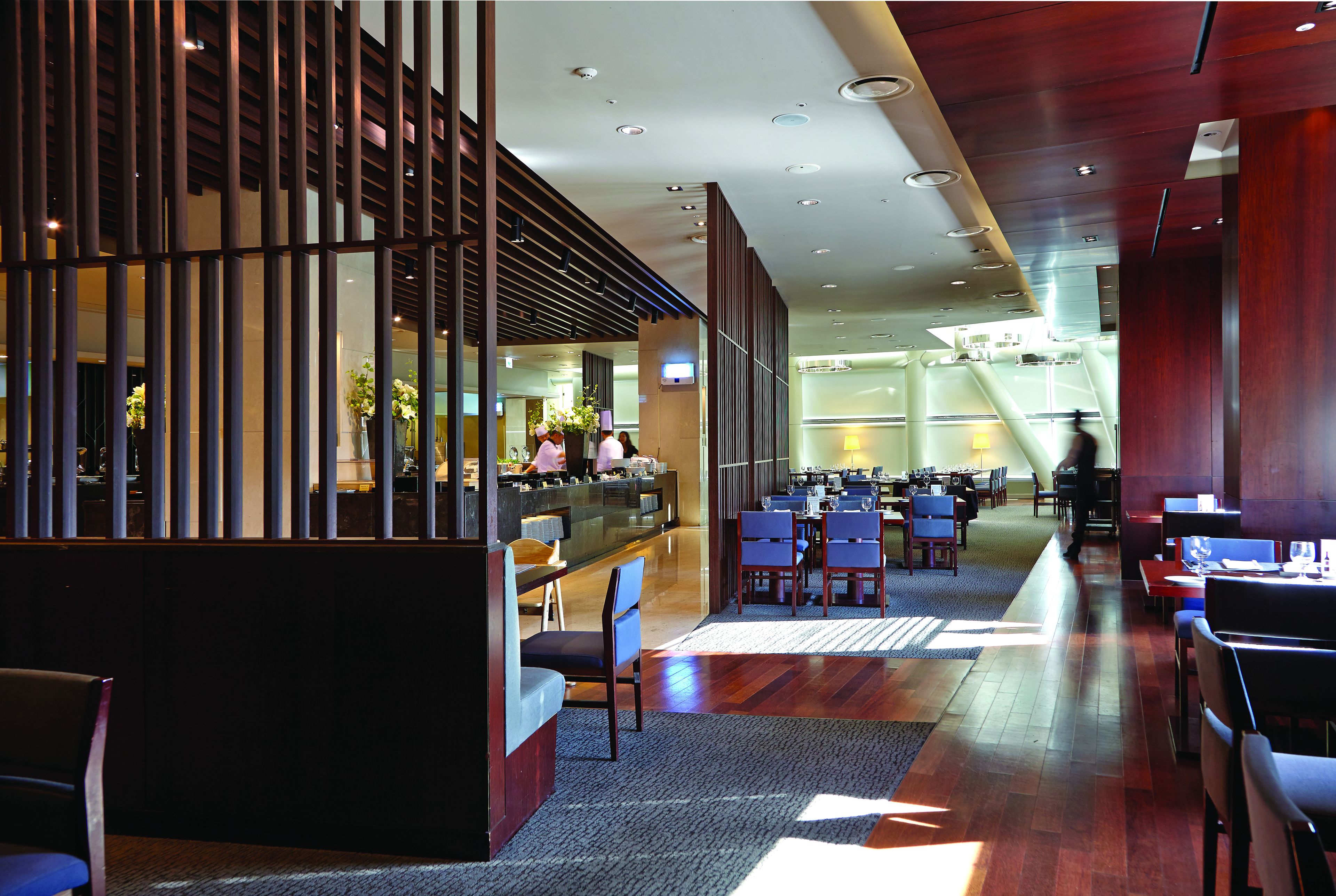 A modern hotel lobby with a reception desk, seating area, and a staircase leading to upper floors.