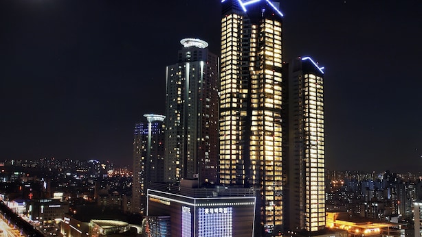 A high-rise building complex with illuminated windows and a prominent digital display.