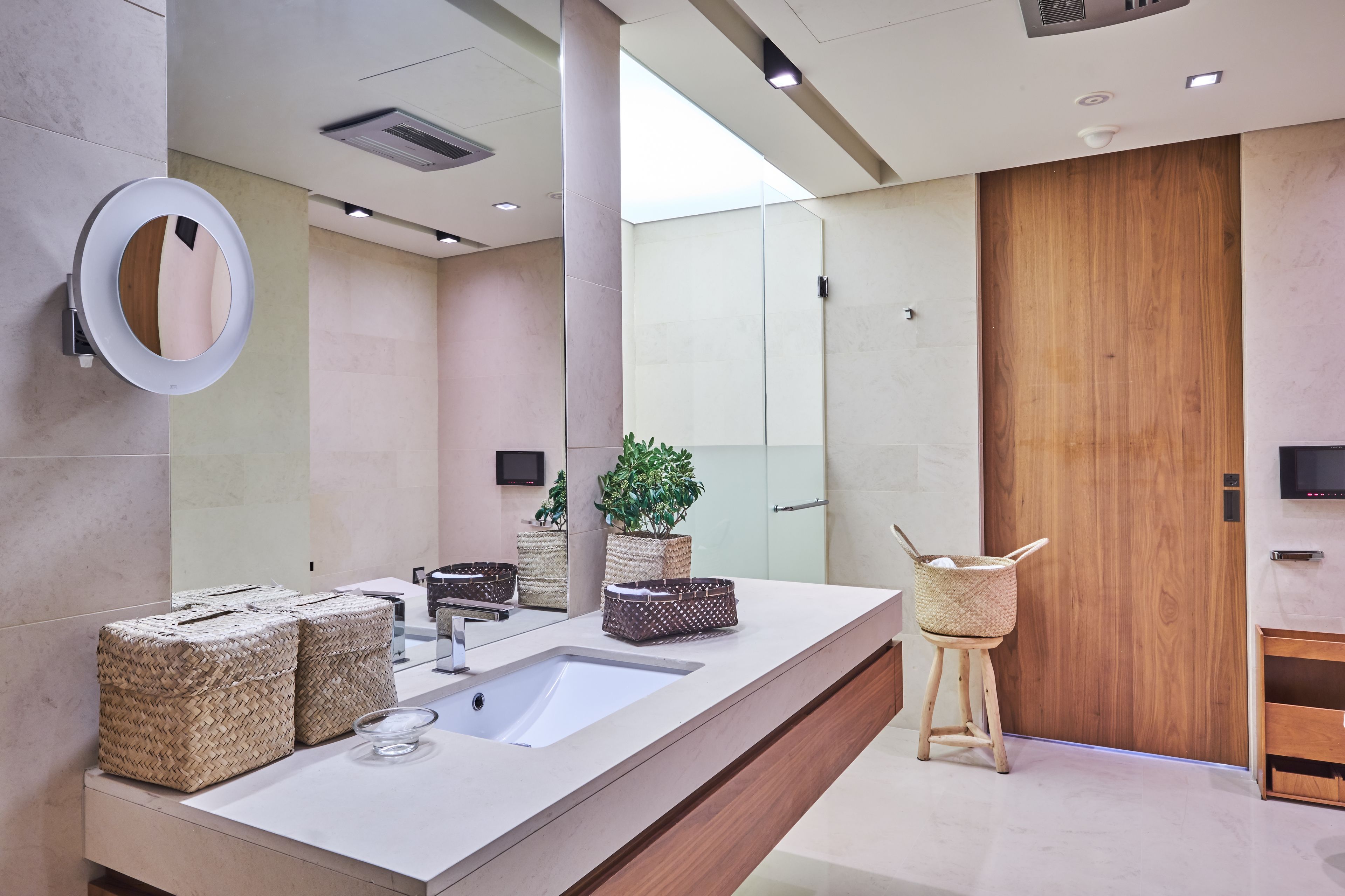 A modern bathroom with a large mirror, a sink, and a wooden door.