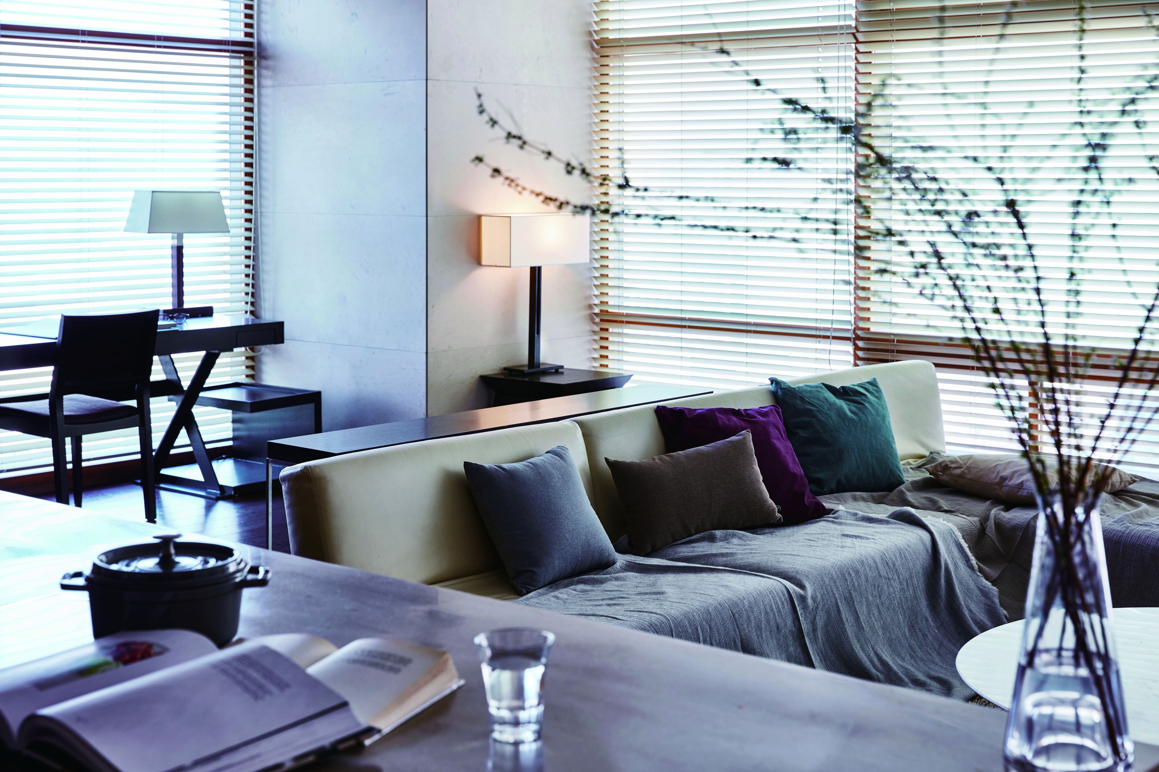 A modern living room with a sofa, a dining table, and a lamp.