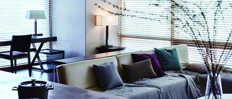 A modern living room with a sofa, a dining table, and a lamp.