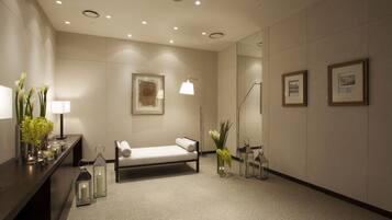 Una habitación de hotel moderna con una cama, lámparas de noche, un jarrón con flores y cuadros en la pared.