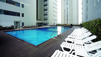 A swimming pool with lounge chairs and a wooden deck.