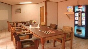 A conference room with a long table, chairs, a chessboard, a Pepsi vending machine, and a thermostat on the wall.