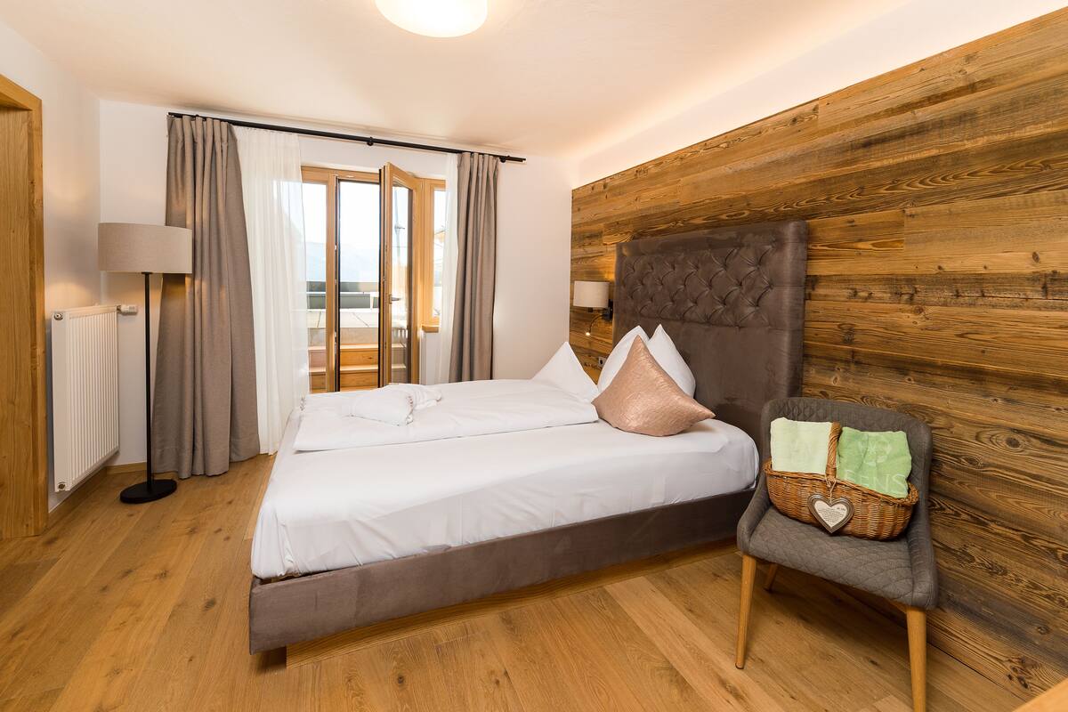 Een slaapkamer met een bed, een stoel, een lamp en een houten wand.