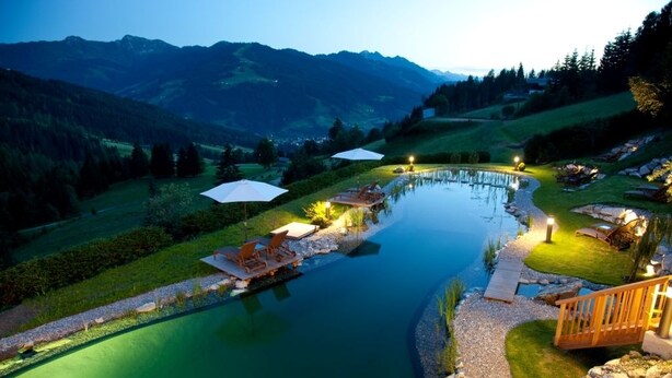 A lakeside resort with a wooden deck, lounge chairs, and a small boat dock.