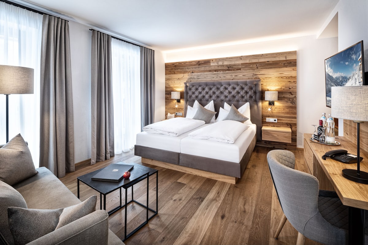 Een moderne hotelkamer met een groot bed, een bureau, een stoel en een bank.