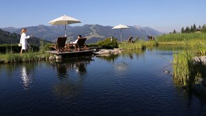 A serene lakeside setting with a wooden dock, lounge chairs, and umbrellas.