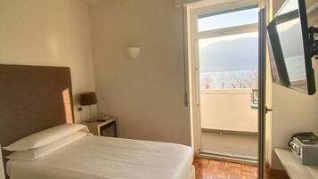 Ein Hotelzimmer mit Bett, Nachttisch, Fernseher und Blick ins Freie.