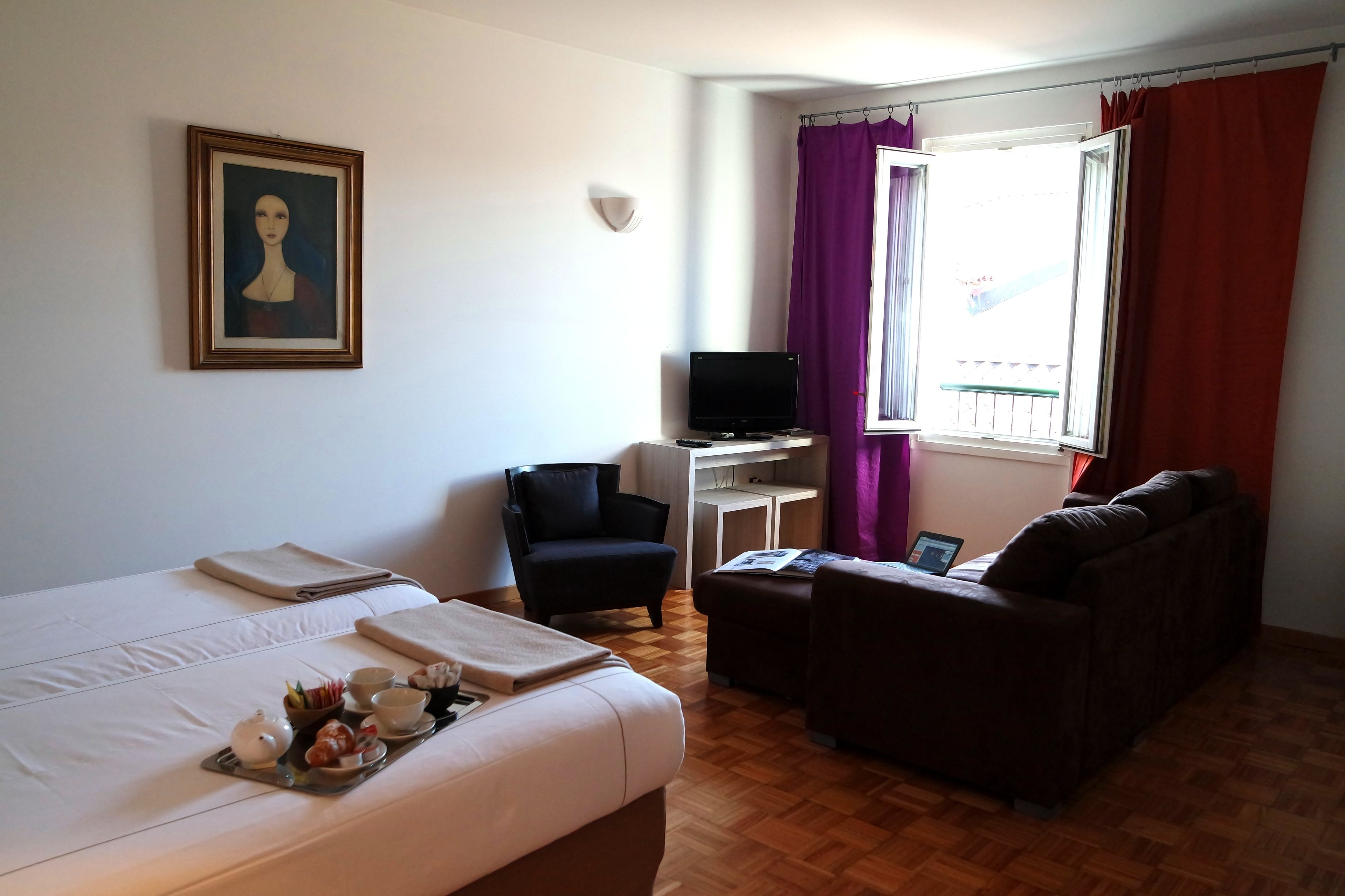 Ein Hotelzimmer mit Bett, einer Couch, einem Fernseher und einem Schreibtisch.
