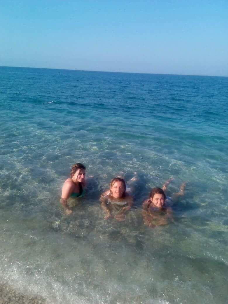 Três pessoas em águas cristalinas na praia.