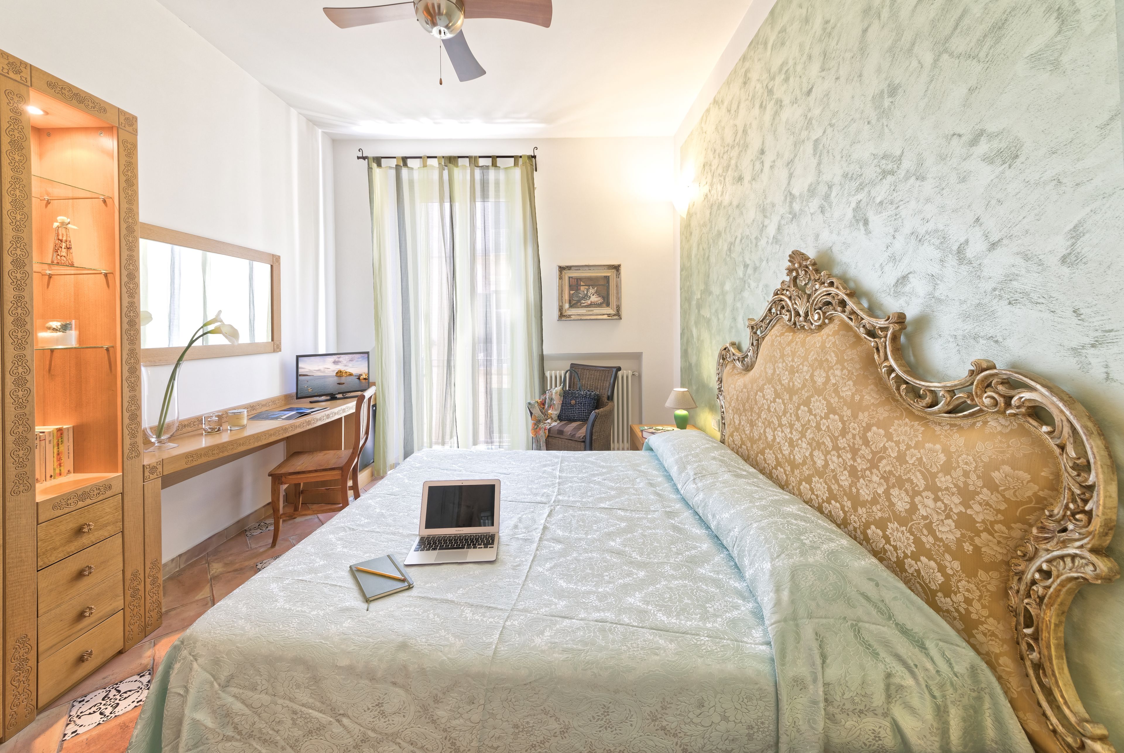 Een slaapkamer met een bed, een bureau en een laptop.