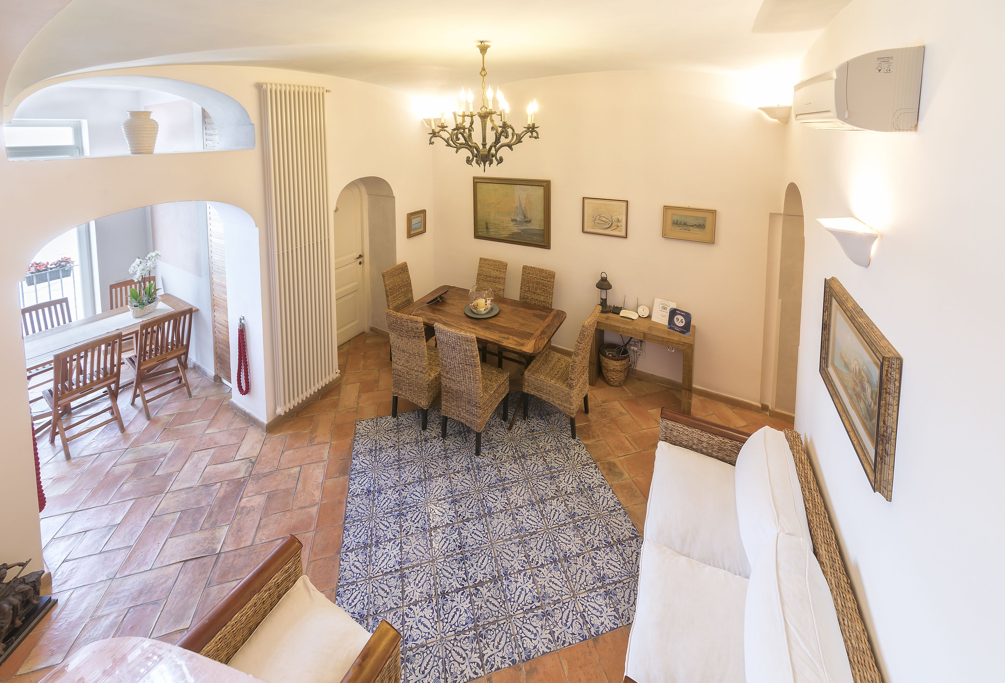 A dining area with a wooden table and chairs, a chandelier, and a patterned rug.