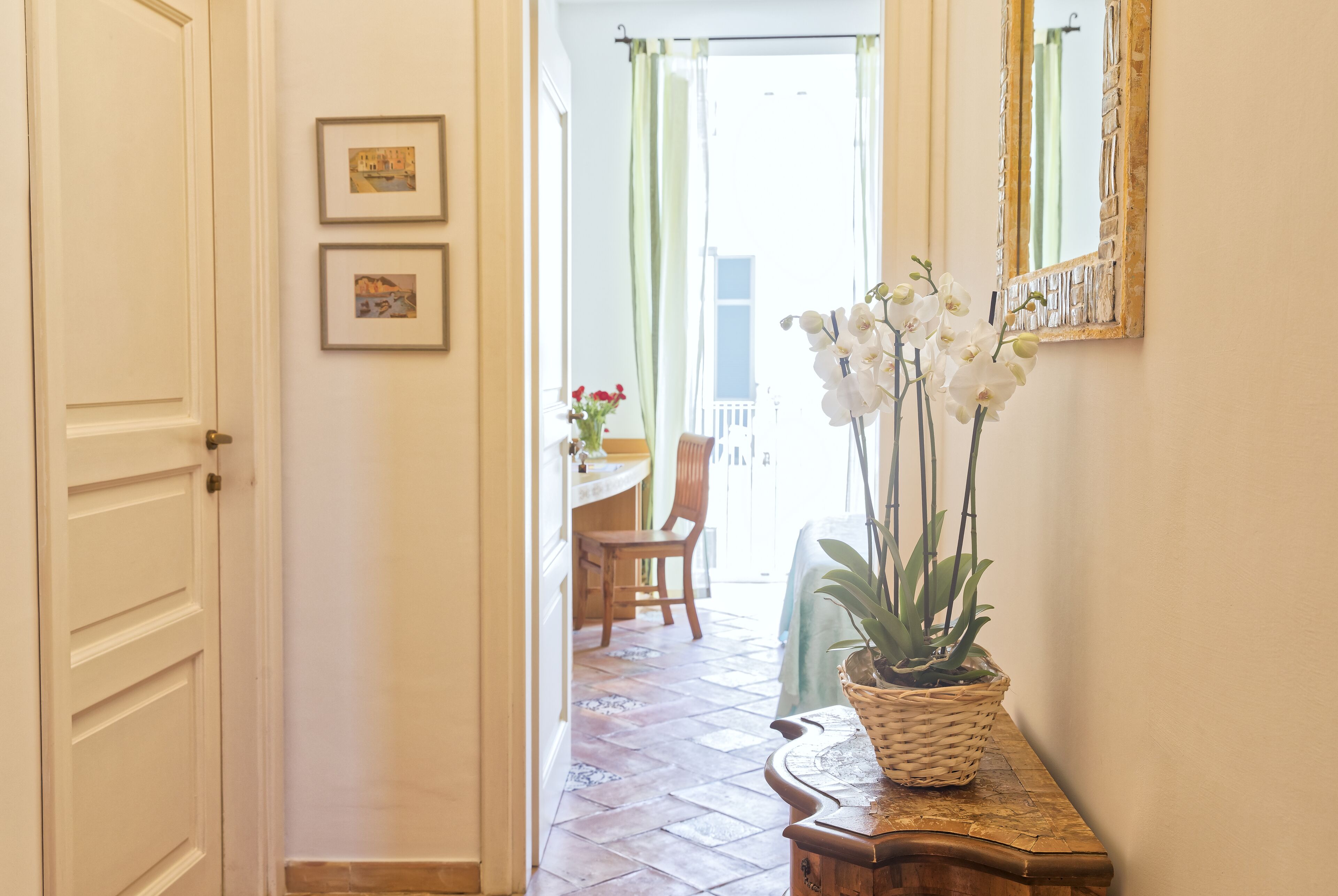 A hallway with a door, a wall-mounted mirror, and a potted plant.
