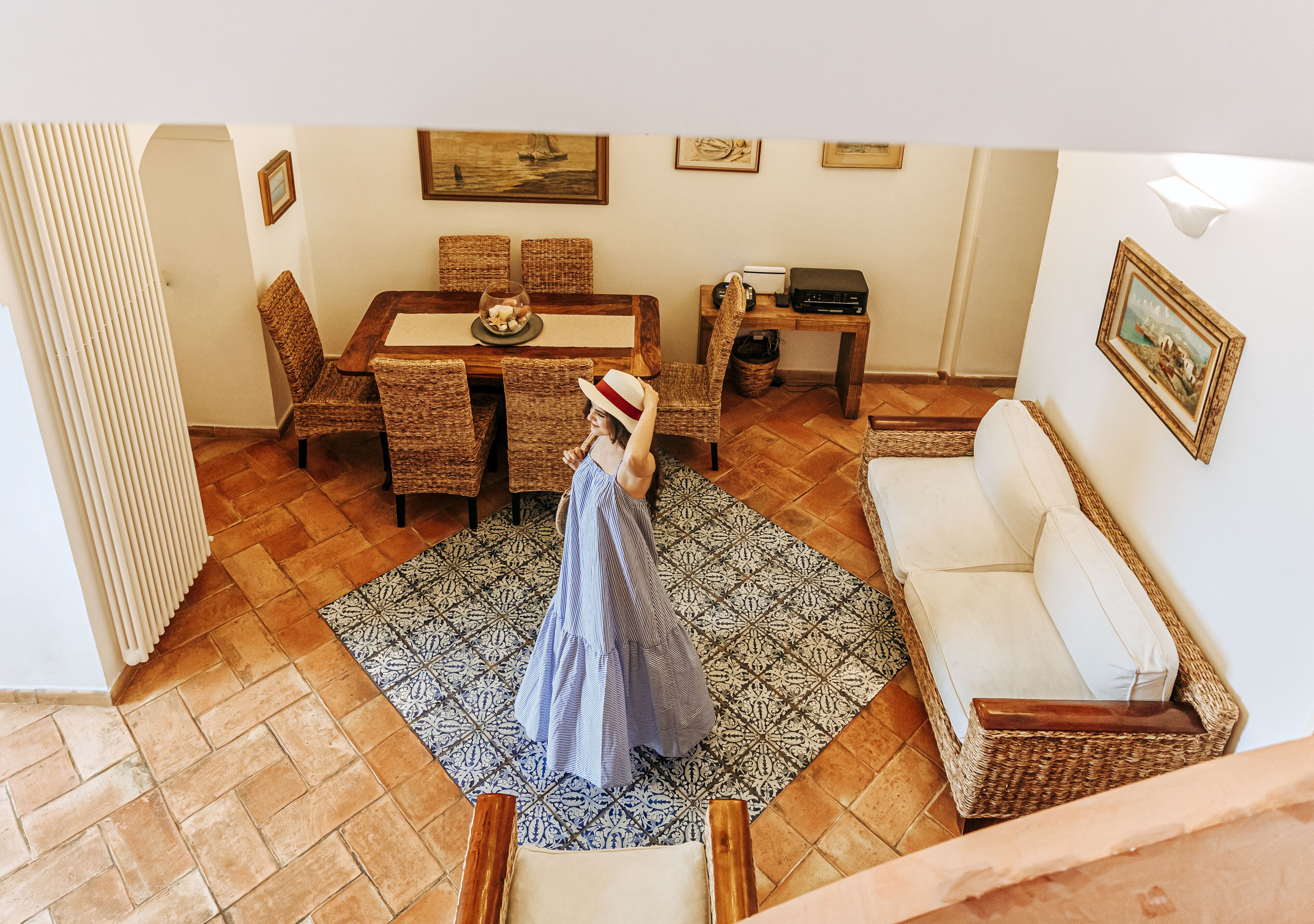 Un'area pranzo con tavolo in legno, sedie in vimini e tappeto decorato.