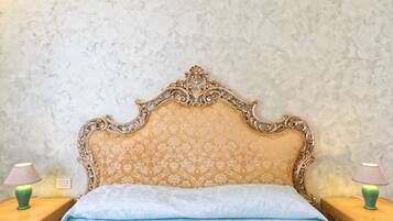 A bedroom with a large ornate bed, two bedside tables with lamps, and a textured wall.
