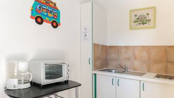 A kitchenette with a toaster, a coffee maker, a sink, and a tiled backsplash.