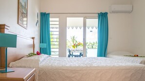 Quarto de hotel com duas camas, uma escrivaninha, um abajur e vista para o exterior.