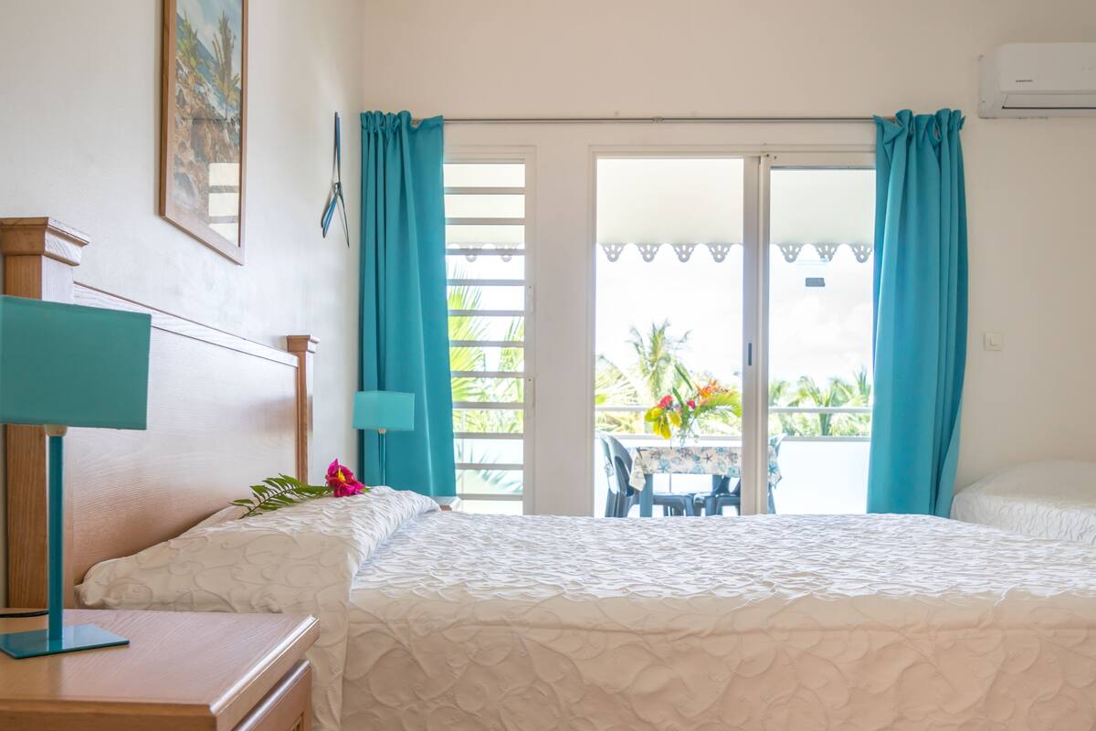 Habitación de hotel con dos camas, un escritorio, una lámpara y vistas al exterior.