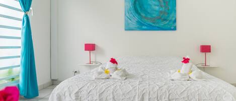 A hotel room with a large bed, two bedside tables with lamps, a painting on the wall, and a window with curtains.