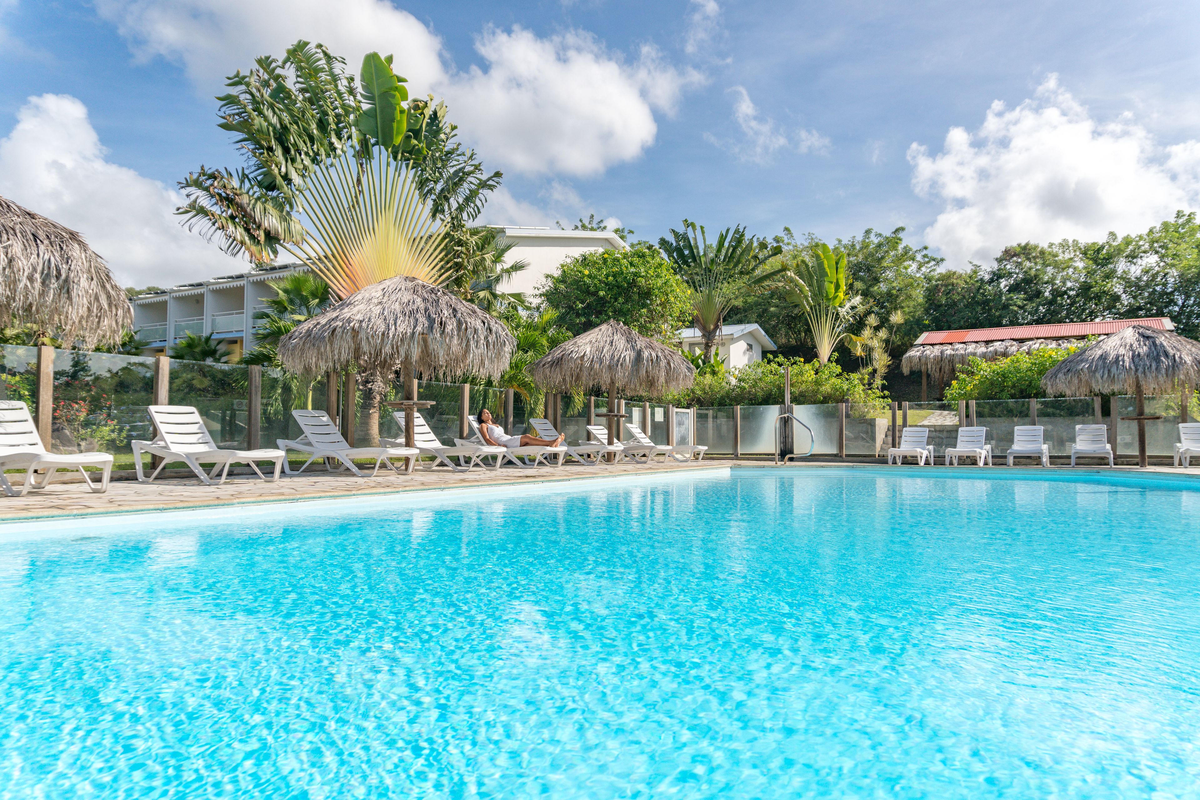 A swimming pool with lounge chairs and thatched umbrellas.