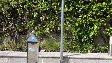 Un panneau de signalisation indiquant un espace de stationnement, doté d’un code QR et d’une borne de recharge.