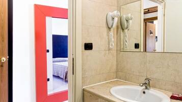 Un baño con lavabo, dos secadores de pelo y un espejo.