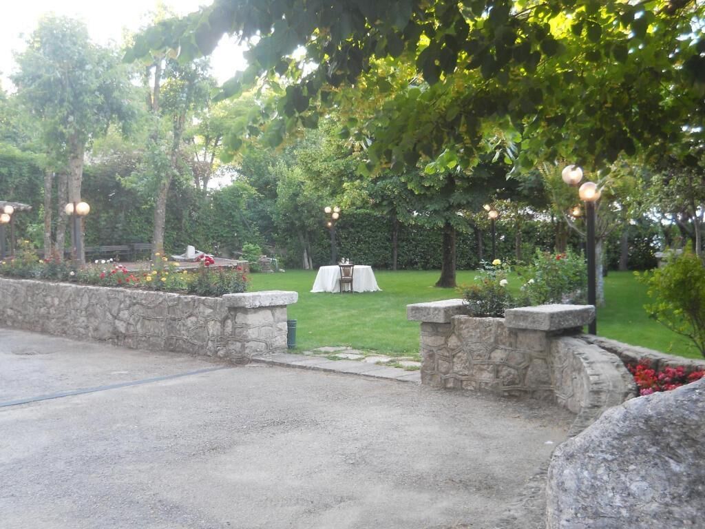 An outdoor garden area with stone walls, a lawn, and a white table with chairs.