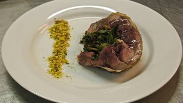 A plate with a piece of meat, greens, and a yellow spice.