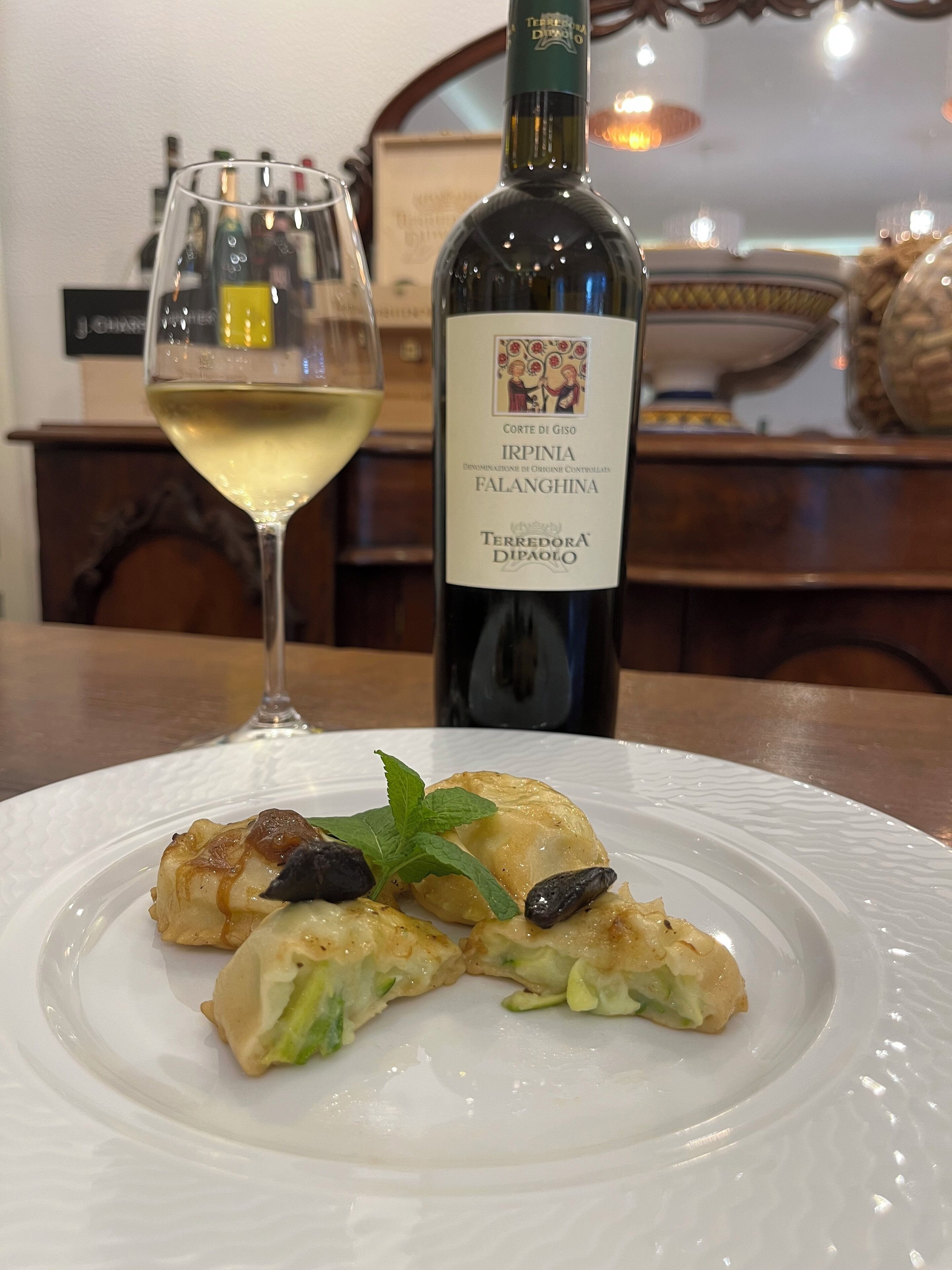 Un plato de comida con una botella y una copa de vino sobre una mesa.