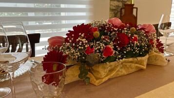 Ein Tisch gedeckt mit Weingläsern, einer Zierblumenkomposition und einer Geschenkbox.