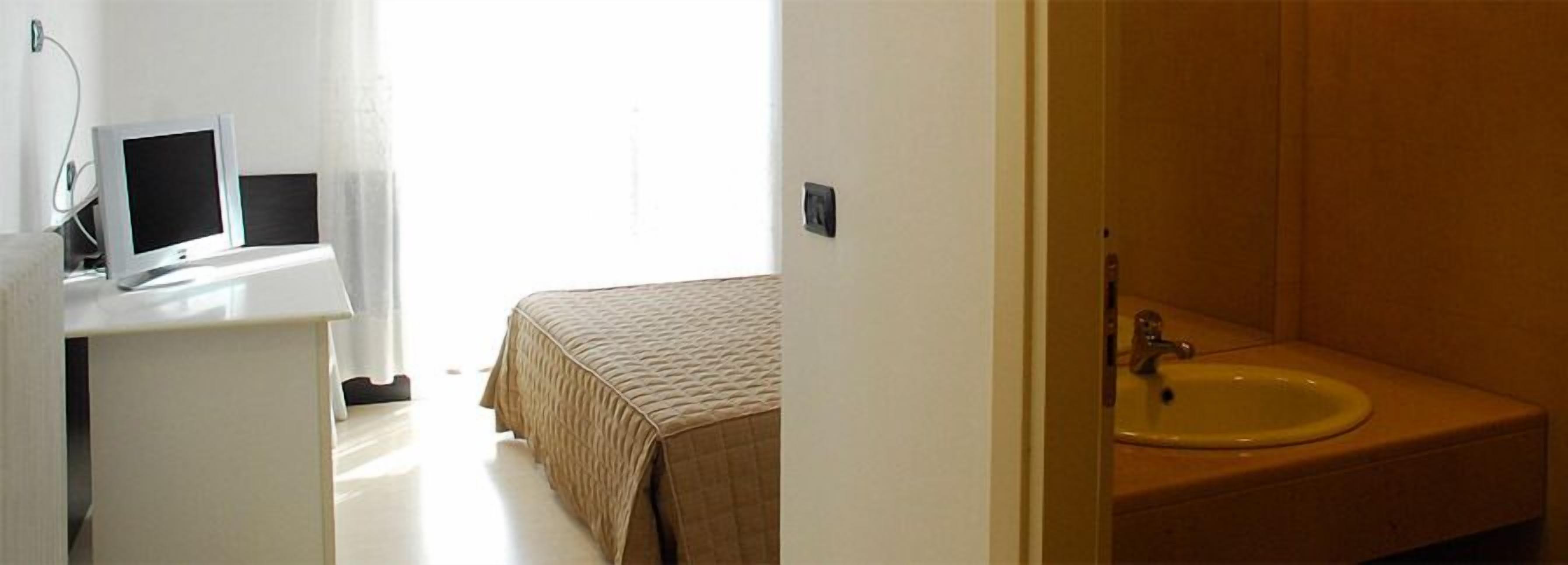 Une chambre à coucher avec un lit, une table de chevet avec une télévision et une salle de bain avec un lavabo.