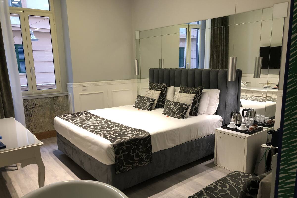 Une chambre d’hôtel moderne avec un grand lit, une table de chevet, une chaise et un miroir.
