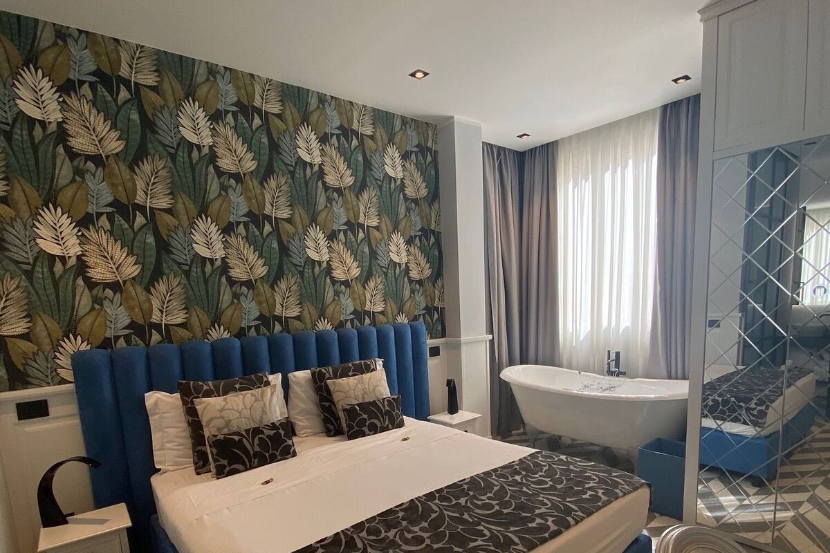 Une chambre d’hôtel moderne dotée d’un grand lit, d’une salle de bain séparée et d’un miroir.