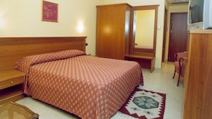 Un dormitorio con cama de madera, un armario, un espejo, un televisor y una alfombra estampada.