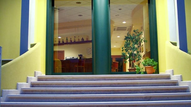 Entrada de un edificio con una escalera que conduce a una puerta de vidrio.