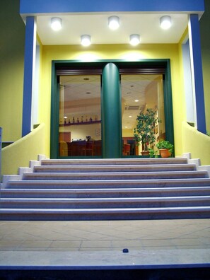 A building entrance with a set of stairs leading up to a glass door. - Hotel Costa d'Oro (Salve)