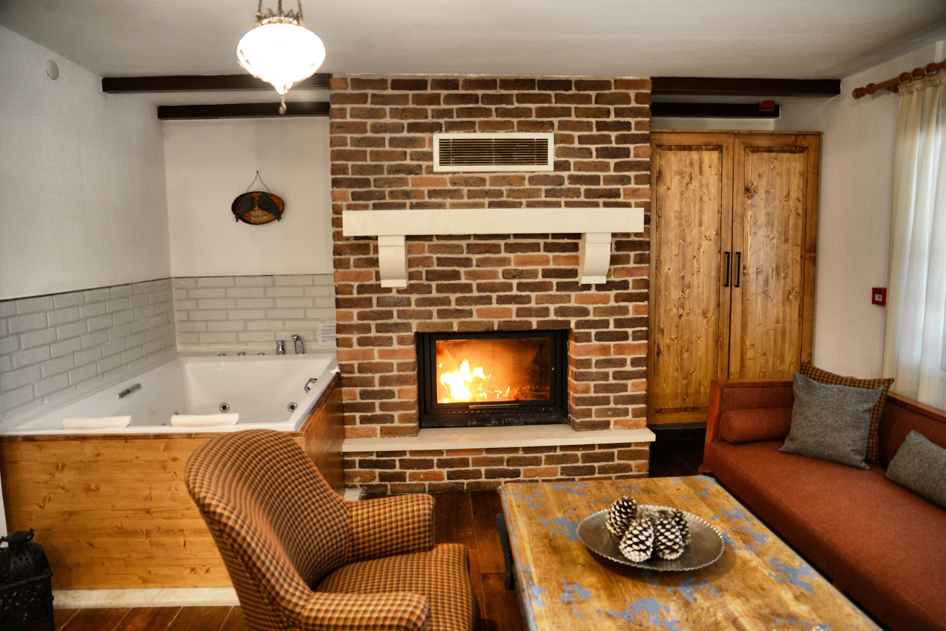 A cozy living room with a fireplace, a sofa, a checkered chair, and a wooden table.
