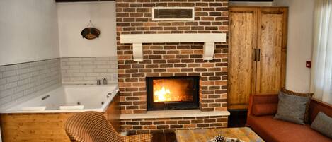 A cozy living room with a fireplace, a sofa, a checkered chair, and a wooden table.