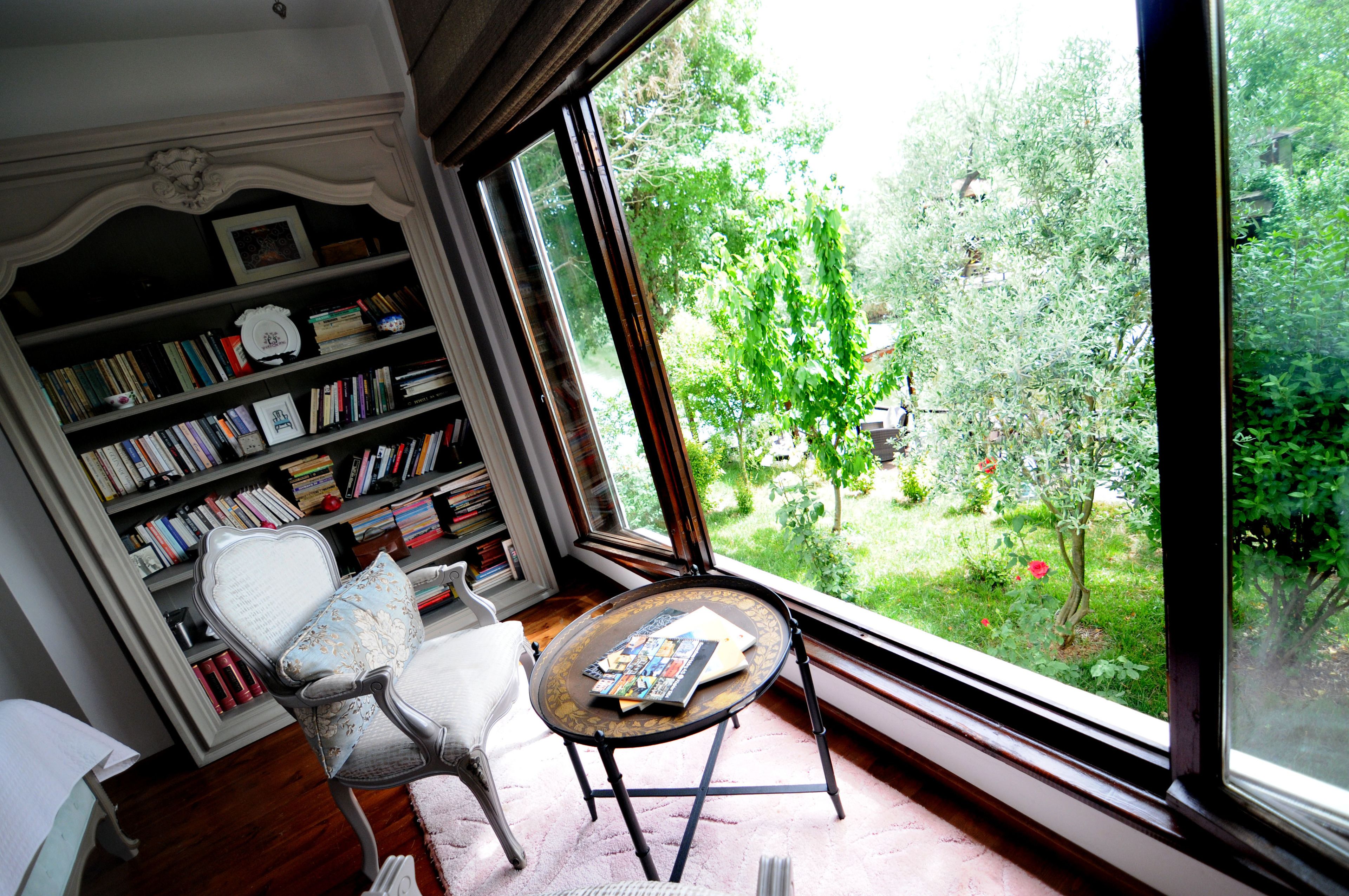 A room with a large window, a bookshelf, a chair, and a small table.