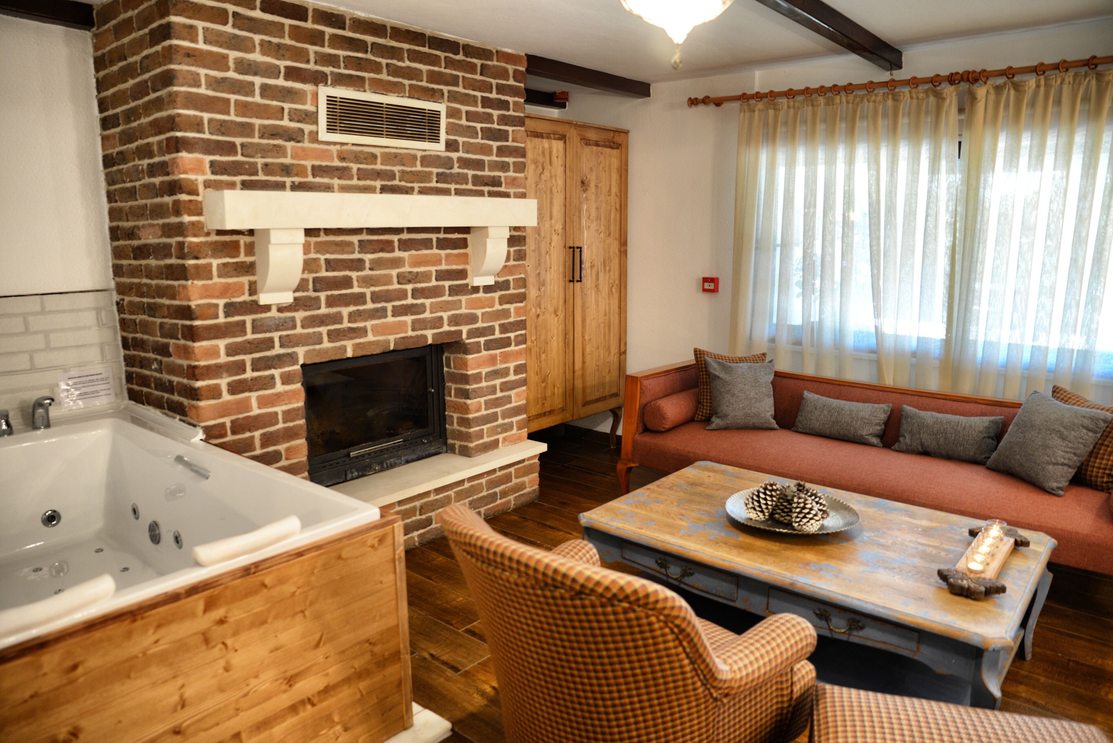 A living room with a brick fireplace, a sofa, a coffee table, and a wooden bathtub.