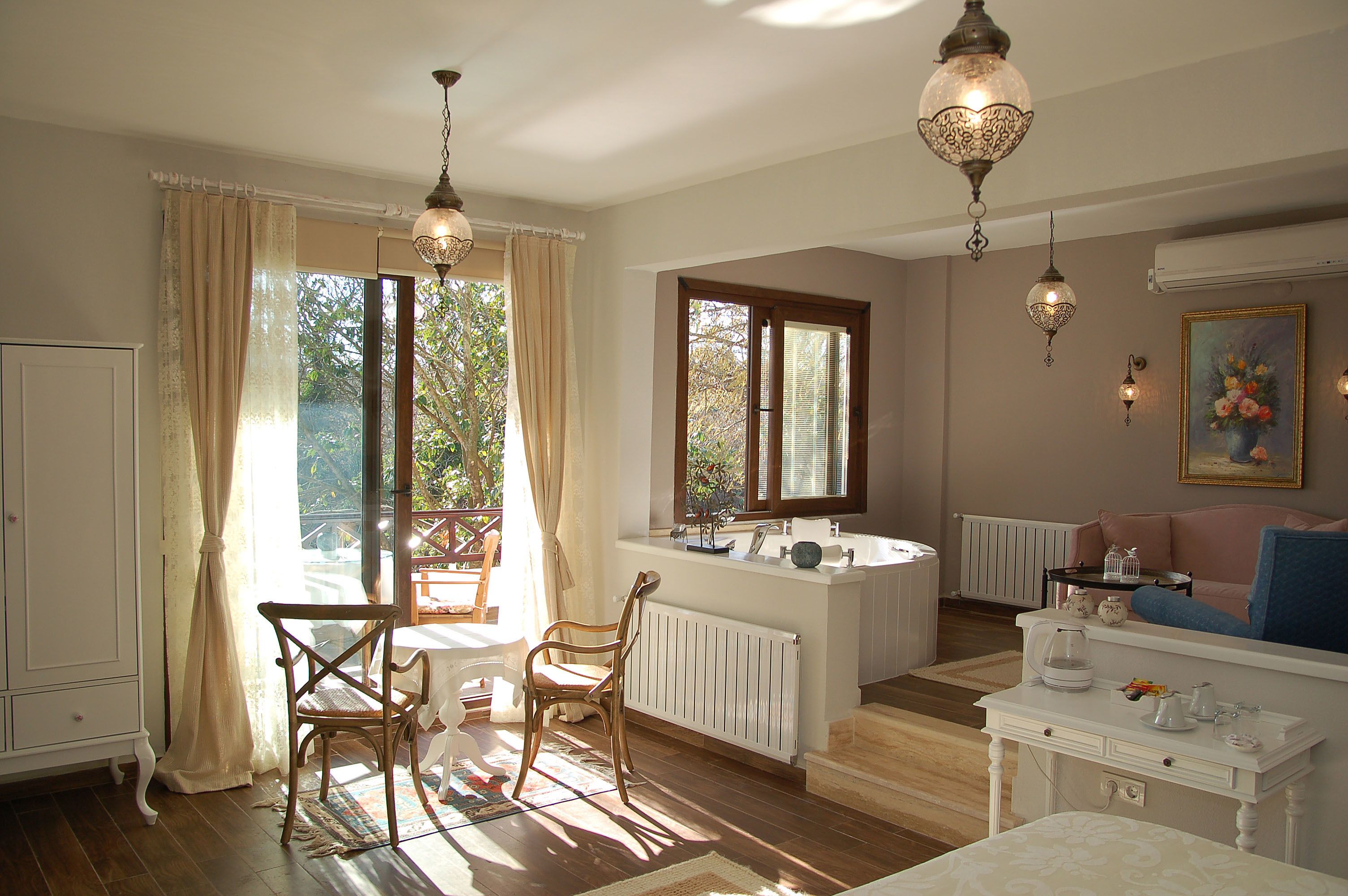 A well-lit room with a wooden floor, a white radiator, a wooden chair, a white table, and a blue sofa.