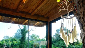 Comedor con vista a un río, techo de madera y un adorno de atrapasueños.