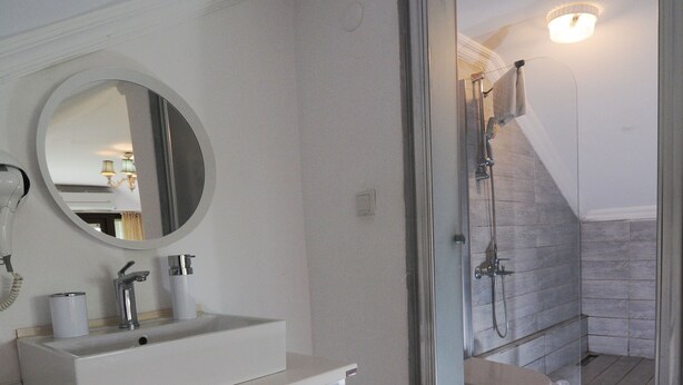 A modern bathroom with a white vanity, a round mirror, and a shower area. - Beyaz Ev Agva - Adults Only (Sile)