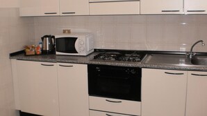 A kitchen with white cabinets, a microwave, a gas stove, and a dishwasher. - RTA Le Corti (Grosseto)