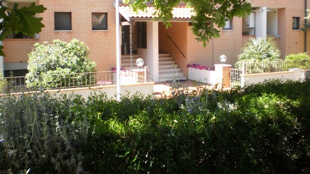 A building with a brick facade, a covered outdoor seating area, and a staircase leading to an upper level. - RTA Le Corti (Grosseto)